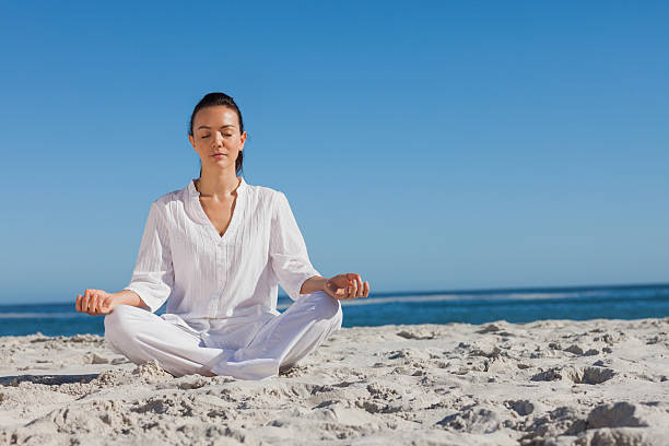 istock Woman in white doing yoga on the beach 507582721