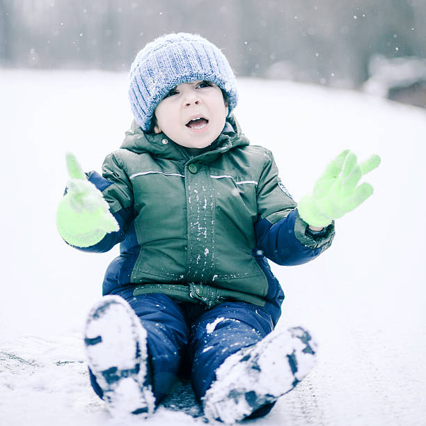 istock Little boy sitting on the road under the snowfall 507584519
