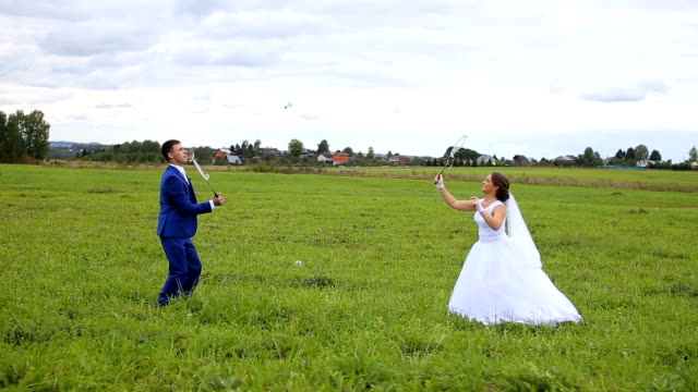 Newlyweds playing badminton on green meadow