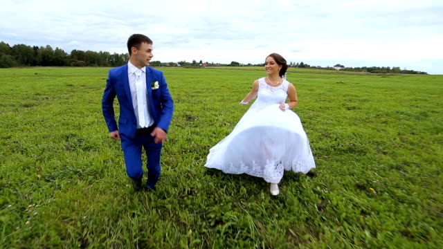 Happy,newlyweds couple running on a green meadow field