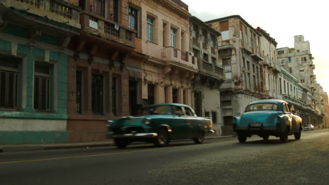 Two vintage cars passing on an old Havana street