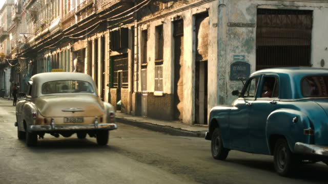 Classical cars passing each other in the old street of Havana