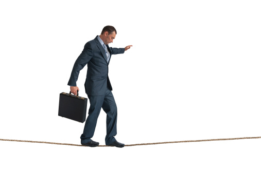 businessman balancing on a tightrope isolated on white