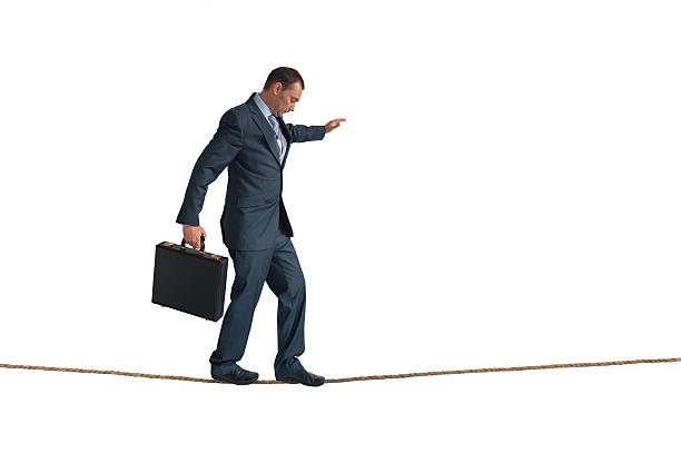 isolated businessman balancing tightrope businessman balancing on a tightrope isolated on white tightrope stock pictures, royalty-free photos & images