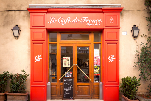 Ste. Maxime, France - March 6, 2014: View to the traditional entrance of the Cafe de France, exists since 1852, in the beautiful town Ste. Maxime at the Mediterranean Sea, South of France. Typical for historical entrances are red wooden signs right and left. Over the door is seen the name of the restaurant.