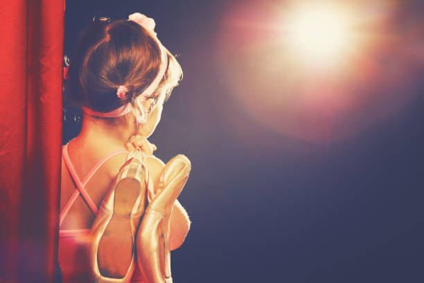 little girl ballerina ballet dancer on stage little child girl ballerina ballet dancer on the stage in red side scenes and looking in odeum dark pink dress stock pictures, royalty-free photos & images