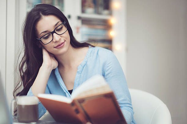 istock Young woman reading a book at home 507630086