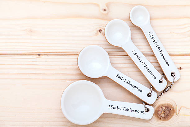 Ceramic measurement spoons on pinewood background linked together and viewed from above.