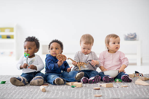 Babies playing together in preschool. Babies playing with toys indoors at a daycare. preschool building photos stock pictures, royalty-free photos & images