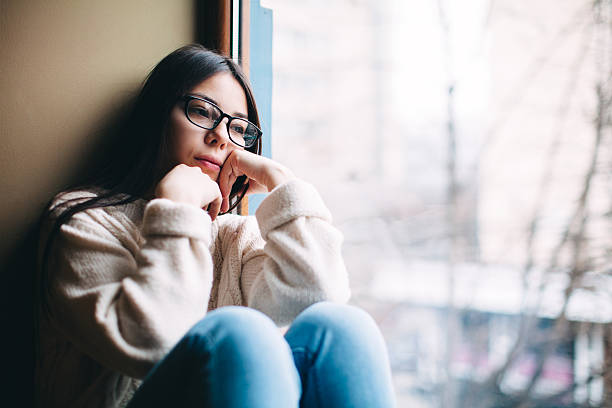 istock sad girl looking out the window 507633424