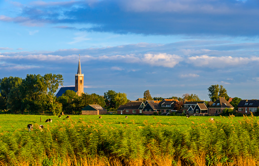 Small village with a church in summer setting, shortly before sunset. Location is Schermerhorn, Netherlands
