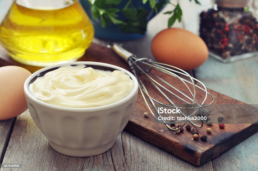 Homemade mayonnaise Homemade mayonnaise in bowl with oil, eggs and spice on wooden background Mayonnaise Stock Photo