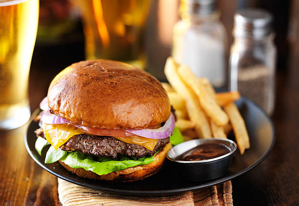 cheeseburger and fries on restaurant table cheeseburger and fries on plate served with beer at restaurant burger stock pictures, royalty-free photos & images