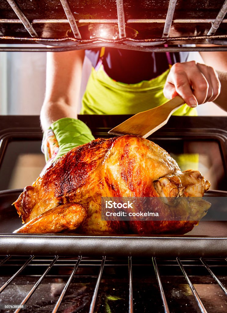 Cooking chicken in the oven at home. Housewife prepares roast chicken in the oven, view from the inside of the oven. Cooking in the oven. Adult Stock Photo