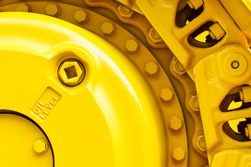 Track drive gear, bulldozer sprocket mechanism, large construction machine with bolts and yellow paint coating, heavy industry, detail 