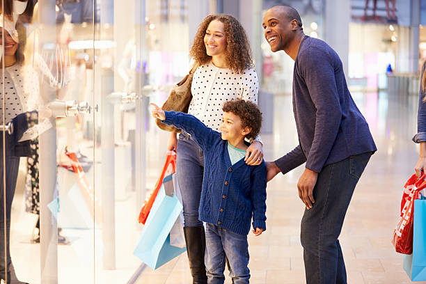 bambino in viaggio al centro commerciale con i genitori - guardare le vetrine foto e immagini stock