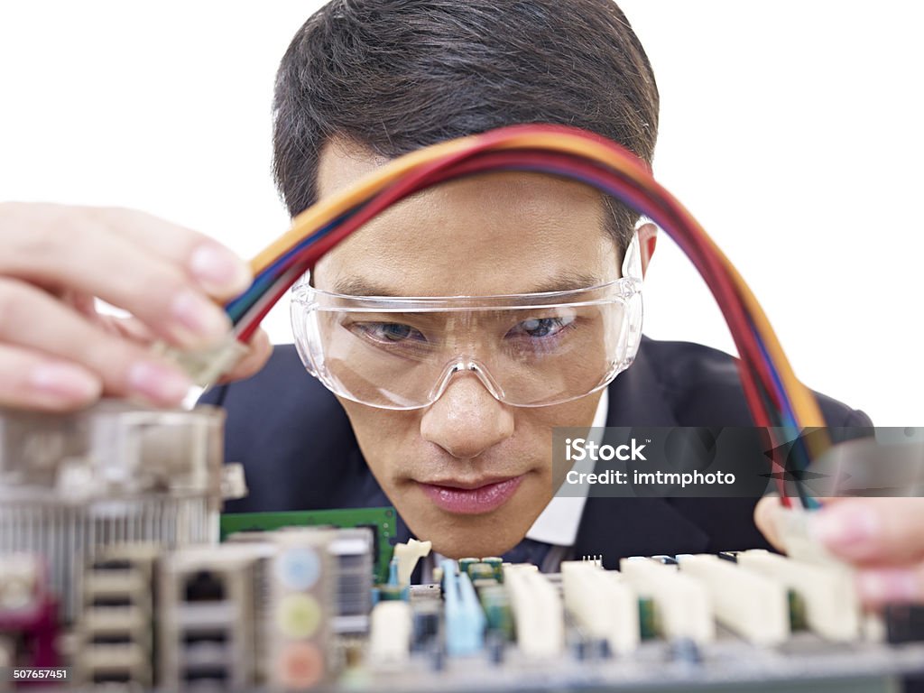 man fixing computer young asian man fixing computer with protective eyewear. Circuit Board Stock Photo