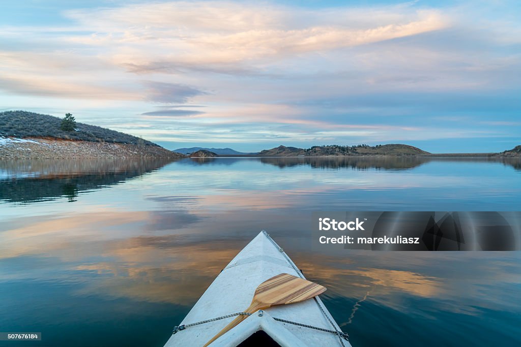 winter canoe paddling in Colorado Horsetooth Reservoir near Fort Collins in northern Colorado, bow view from a decked expedition canoe with a wooden paddle, winter scenery at dusk Colorado Stock Photo