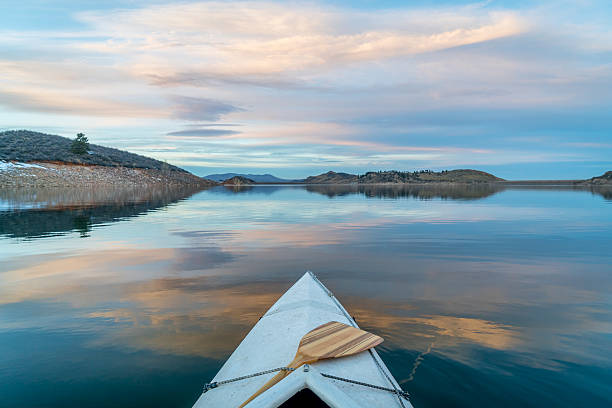 winter canoe paddling in Colorado Horsetooth Reservoir near Fort Collins in northern Colorado, bow view from a decked expedition canoe with a wooden paddle, winter scenery at dusk foothills photos stock pictures, royalty-free photos & images