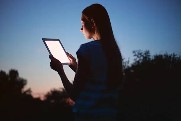 Photo of Young woman using digital tablet at night
