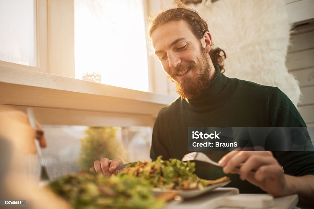 Young happy man enjoying in a healthy meal. Happy man sitting at the restaurant and having salad for lunch. Eating Stock Photo