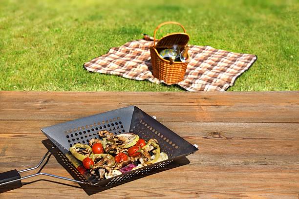 Picnic and BBQ scene Summer Picnic Scene. Grill Pan with grilled vegetables on the wood table. Basket with wine and wineglass on the blanket. metal grate photos stock pictures, royalty-free photos & images