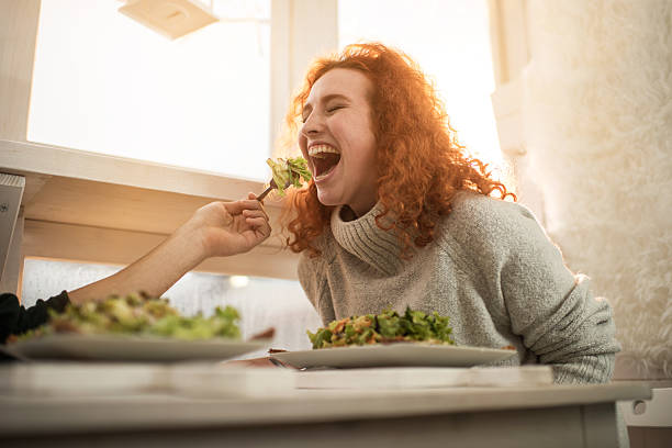 Young cheerful woman being fed by unrecognizable man.