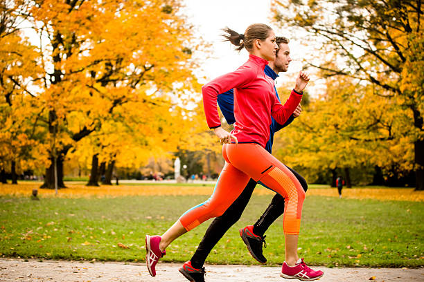 casal jogging no outono natureza - running women jogging profile imagens e fotografias de stock
