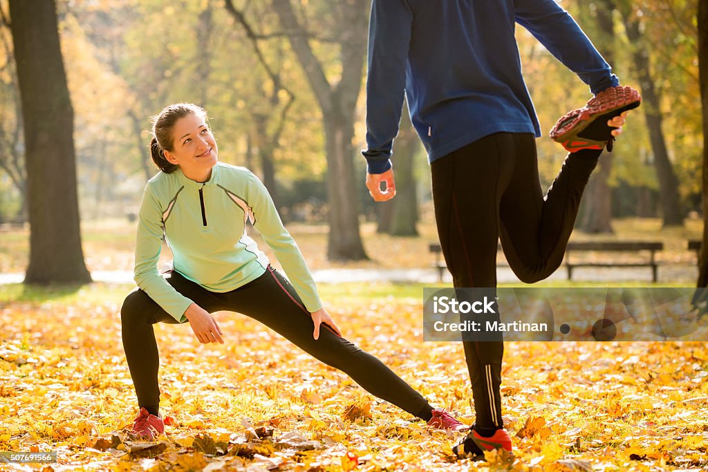 Warm up before jogging Young couple stretching legs before jogging in autumn nature Active Lifestyle Stock Photo