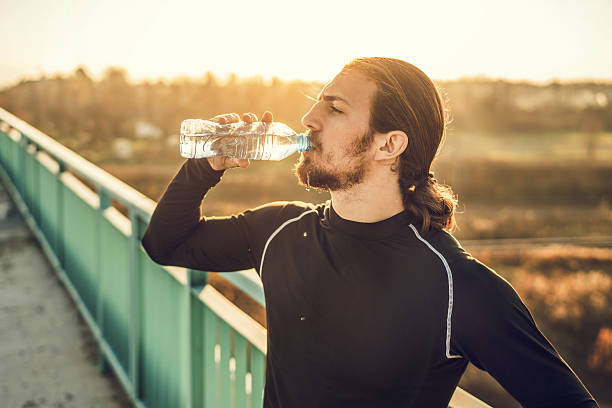 istock Athletic man drinking water on the bridge at sunset. 507706540