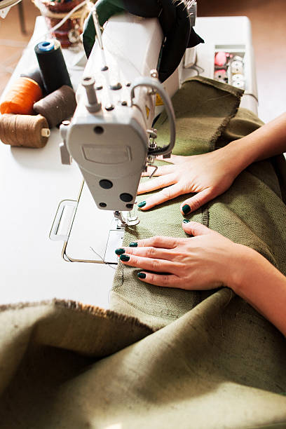 seamstress sews clothes seamstress sews clothes. Workplace of tailor - sewing machine, rolls of of thread, scissors. machine sewing white sewing item stock pictures, royalty-free photos & images