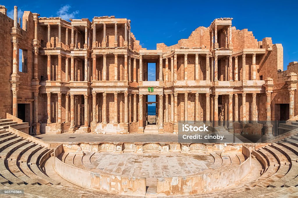 Roman Amphitheatre of Sabratha , Libya , Tripolitania Magnificent columns on an ancient building facade. A public building of Sabratha, Libya. The theatre was built in 175-200 AD, so it was started by Emperor Marcus Aurelius; the construction was continued by his son Commodus and completed with a lavish proscaenium by Emperor Septimius Severus who was born in Leptis Magna; this time frame is applicable also to the enlargement of the theatre of Ostia.  Libya Stock Photo