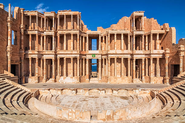 Roman Amphitheatre of Sabratha , Libya , Tripolitania Magnificent columns on an ancient building facade. A public building of Sabratha, Libya. The theatre was built in 175-200 AD, so it was started by Emperor Marcus Aurelius; the construction was continued by his son Commodus and completed with a lavish proscaenium by Emperor Septimius Severus who was born in Leptis Magna; this time frame is applicable also to the enlargement of the theatre of Ostia.  libyan culture stock pictures, royalty-free photos & images