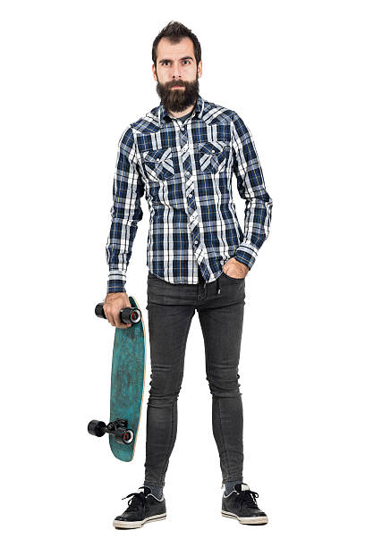 istock Funny hipster carrying skateboard in one hand looking at camera 507710698