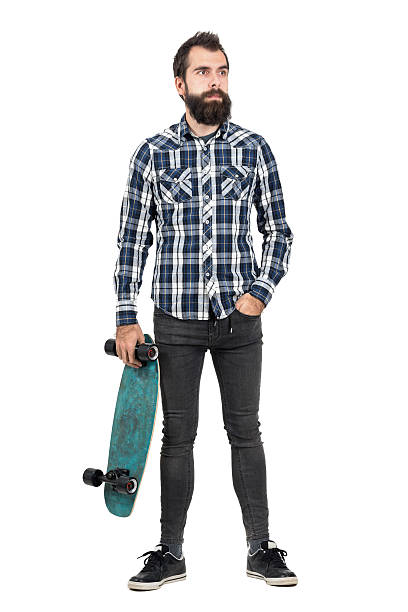 istock Confident hipster carrying skateboard in one hand looking away 507710742