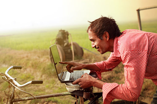 Granjero usando una computadora portátil en el campo photo