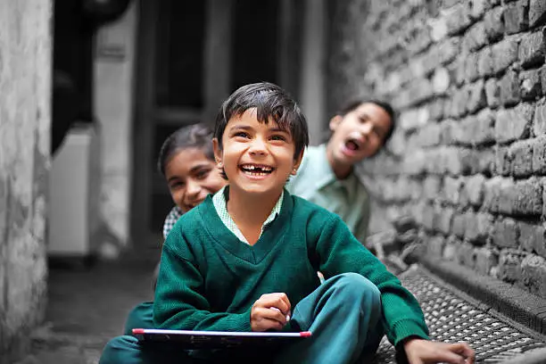 Photo of Little School Girls laughing portrait at home near brick wall