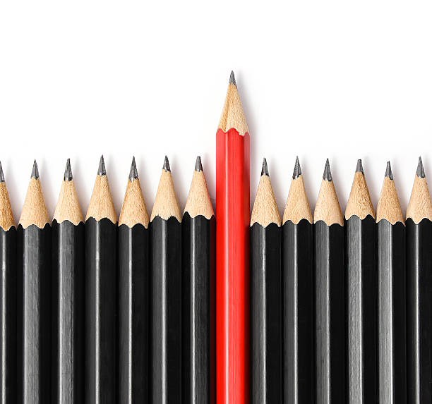 istock Red pencil standing out from identical black fellows. 507717888