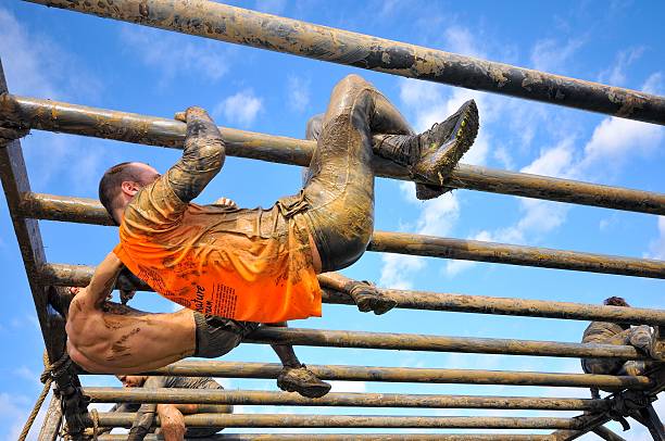 Farinato Race - extreme obstacle race in Gijon, Spain. Gijon, Spain - January 31, 2016: Farinato Race, extreme obstacle race in January 31, 2016 in Gijon, Spain. People jumping, crawling,passing under a barbed wires or climbing obstacles during extreme obstacle race.  obstacle course stock pictures, royalty-free photos & images