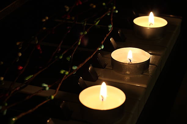 istock Three lighted candles and tree blossom branch on the piano 507722114