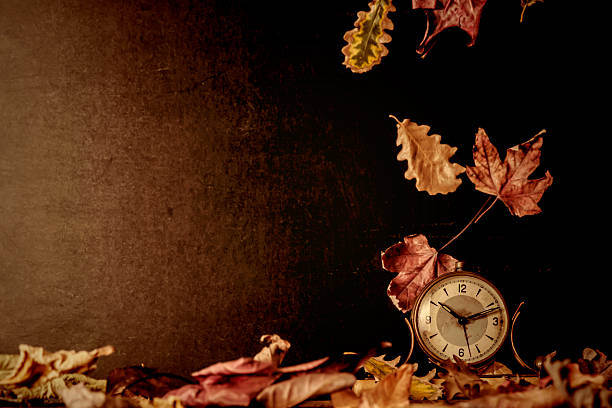 istock Old clock and autumn leaves background 507722360
