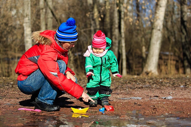 vater und kleine tochter spielen mit wasser im frühling - puddle rain boot water stock-fotos und bilder