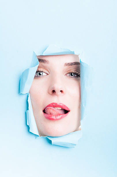 istock Beautiful young woman acting sexy thru torn cardboard 507746202