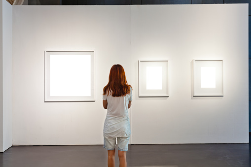One woman looking at white frames in an art gallery