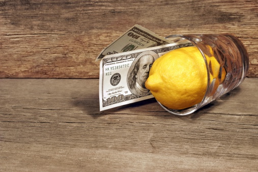 Two hundred dollars and lemon in a glass on the wooden table. Background with space for text or image.