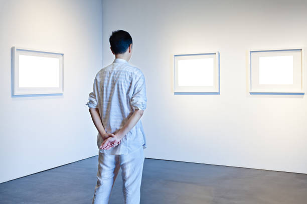 ein mann schaut ein weißen rahmen in kunstgalerie - ausstellung fotos stock-fotos und bilder