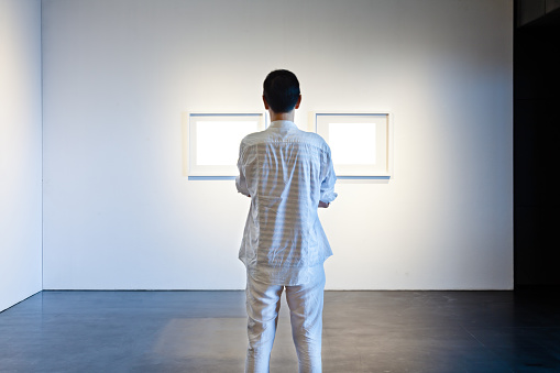 One man looking at white frames in an art gallery
