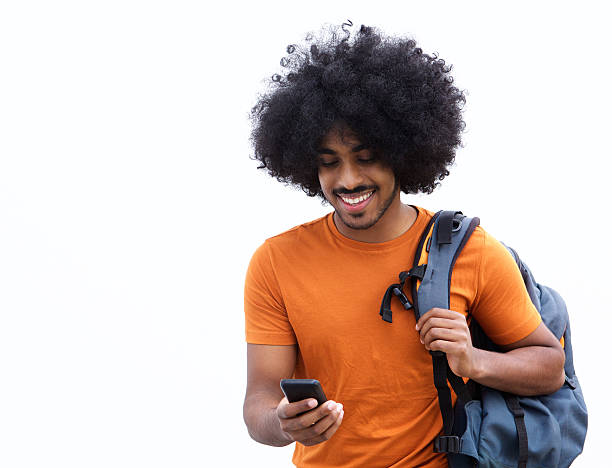Cool young man with bag looking at mobile phone Portrait of a cool young man with bag looking at mobile phone men hairstyle afro cool stock pictures, royalty-free photos & images