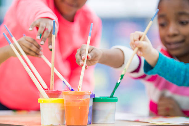Kids have art class, drawing, painting with teacher in workshop. They engage in creative activities and enjoy learning together.