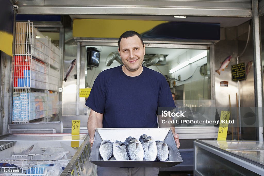 Owner Displaying Fresh Fish In Store Portrait of confident owner displaying fresh fish in store Front View Stock Photo